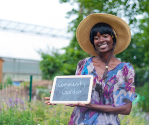 Woman holding a sign that says Community Garden